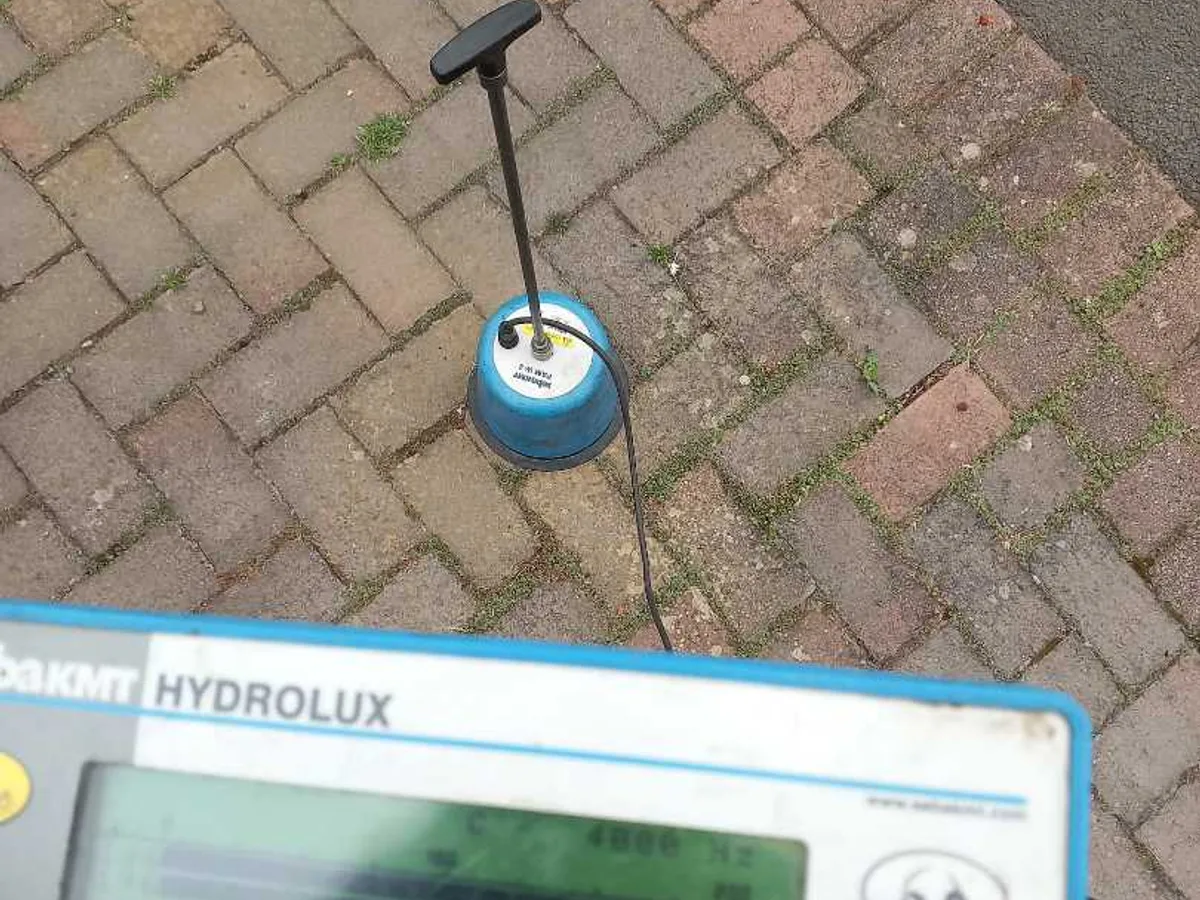 An acoustic ground microphone on a block paved drive, with its listening unit in the foreground.